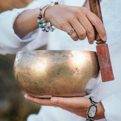 Practitioner using Tibetan singing bowls in a sound healing session at The Well House in Towson, MD, creating calming vibrations to promote relaxation and inner peace.